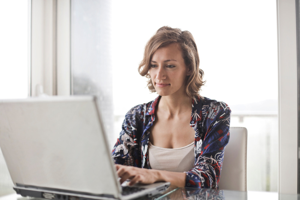 Woman sitting at table researching on a laptop.