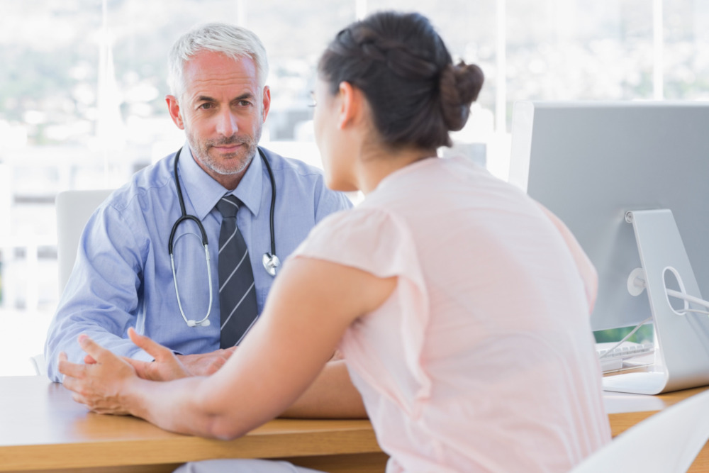 Woman talking to a male doctor in the doctor's office.