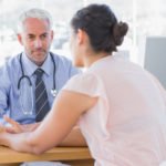 Woman talking to a male doctor in the doctor's office.