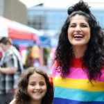 Woman wearing rainbow sweater. MTF breast augmentation.